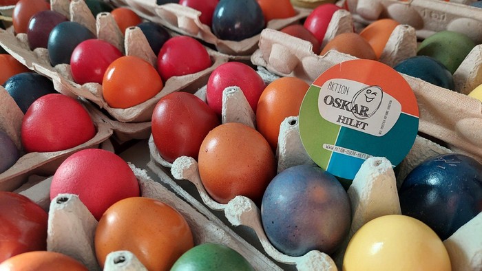 Bunte hartgekochte Eier in Kartons mit einem Markenetikett für Oskar Hilft.
