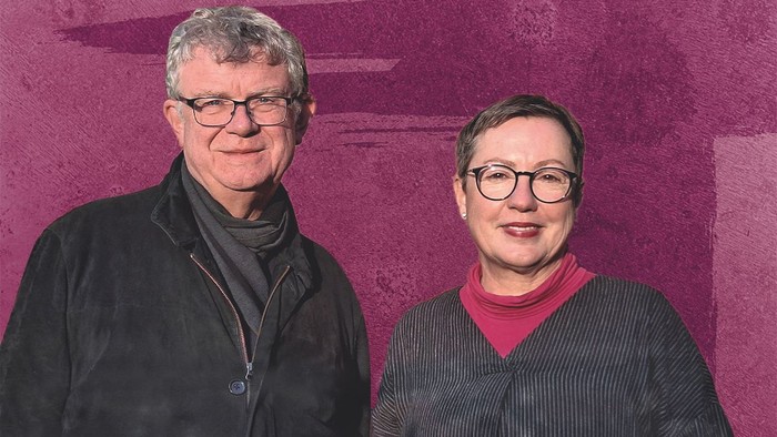 Pröpstin Petra Kallies steht rechts vor einer purpur farbigen Wand mit Kreuz im Hintergrund, neben ihr links steht der katholische Propst Christoph Giering.