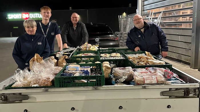 En gruppe mennesker læsser friske fødevarer og forsyninger på en leveringslastbil om natten.