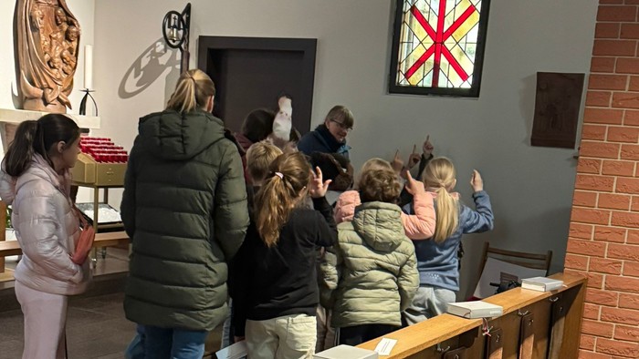 Gruppe von Menschen, die während eines Gottesdienstes oder einer Führung in Kirchenbänken sitzen und religiöse Kunstwerke betrachten.