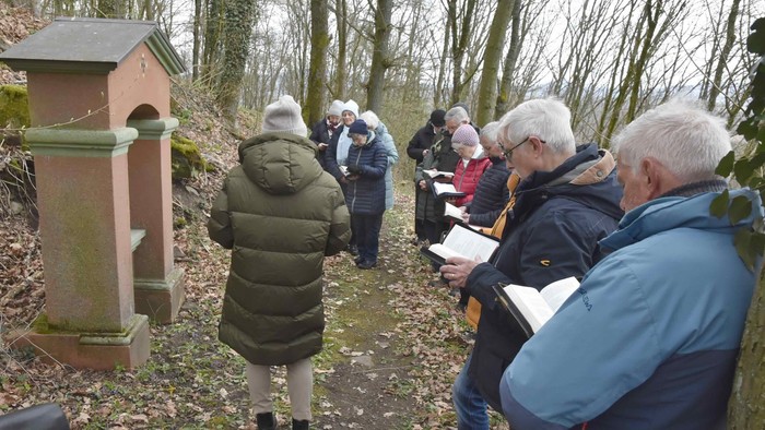Eine Gruppe von Menschen in einem Wald untersucht eine kleine Backsteinstruktur, während sie draußen Notizen macht.