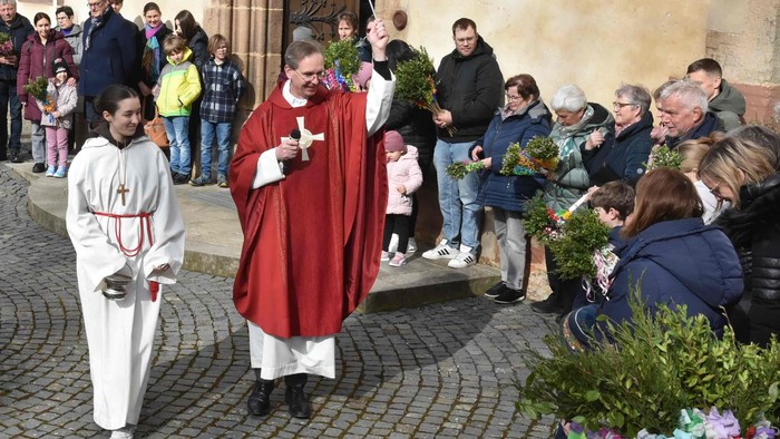 Religiöse Prozession mit Geistlichen und Gemeinde, die Blumenarrangements vor einer Kirche halten.