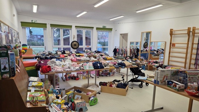 Bewegungsraum der Kita Arche Noah mit Tischen voller Kinderkleidung und Spielzeug anlässlich des Frühlingsbasars