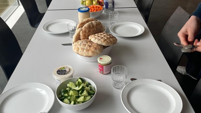 Langer Tisch mit orientalischen Snacks, Pitabrot, Hummus, Salat und Getränken für ein gemeinsames Essen.