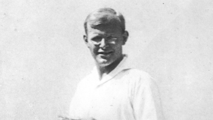 Ein junger Mann mit kurz geschnittenem Haar und weißem Hemd lächelt in die Kamera.