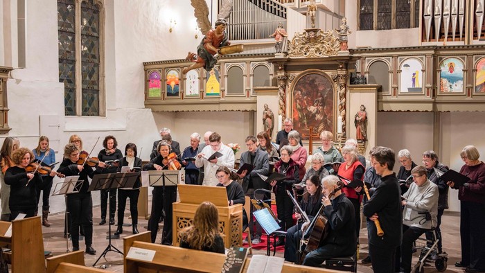Ein gemischter Chor und Instrumentalisten im Halbkreis in einer Kirche