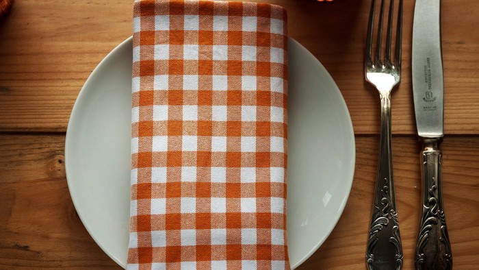 Ein weißer Teller mit rot-karierter Serviette und Besteck