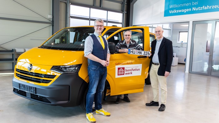 Drei Männer um einem gelben Bus