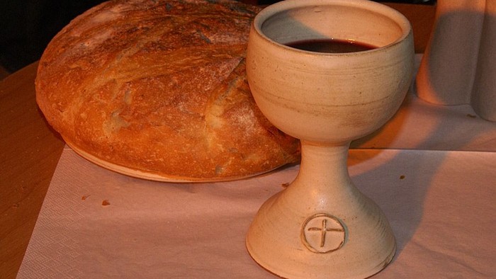 Ein Krug mit Wein und ein Brotlaib auf einem Tisch