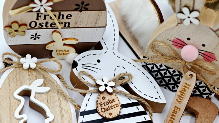 Bunte Oster-Deko aus Holz mit Motiven wie Hasen, festlichen Botschaften wie „Frohe Ostern“ und Jute-Anhängern.