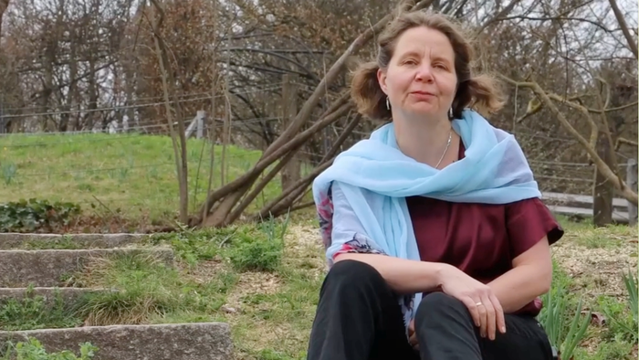 Pfarrerin Claudia Mieth auf einer Treppe in frühlingshafter Landschaft sitzend