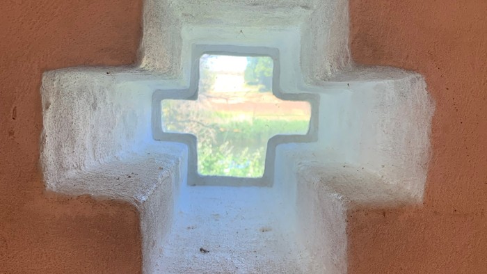 En lysende hvid korsformet vindueskarm på rød mur