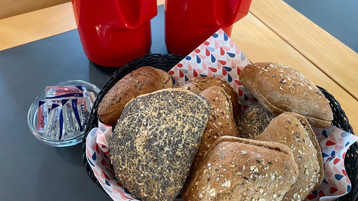 Kurv med brødbolle og to røde krydderidispensere