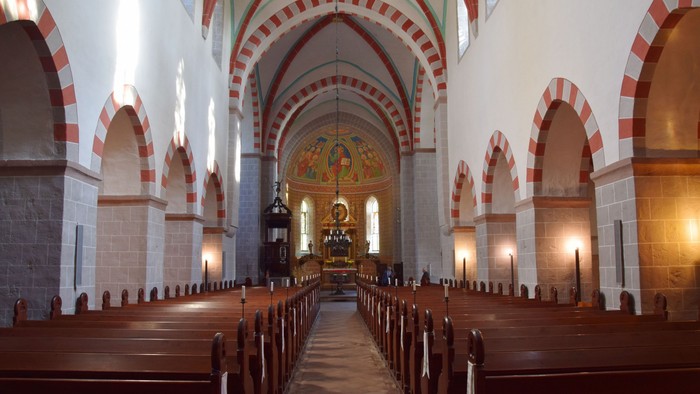 Innenraum einer Kirche mit Holzgalerie und hohen Bögen