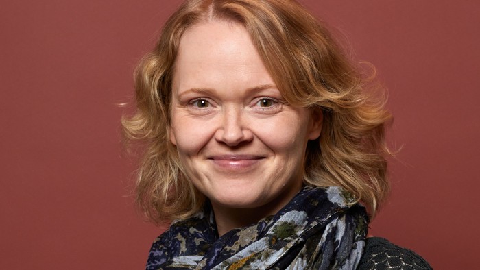 En kvinde med rødt hår og en mørk skjorte og skjorte.