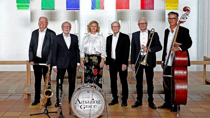 Et jazzensemble ved navn Amazing Grace poser sammen med deres instrumenter i en farverig og livlig omgivelse.