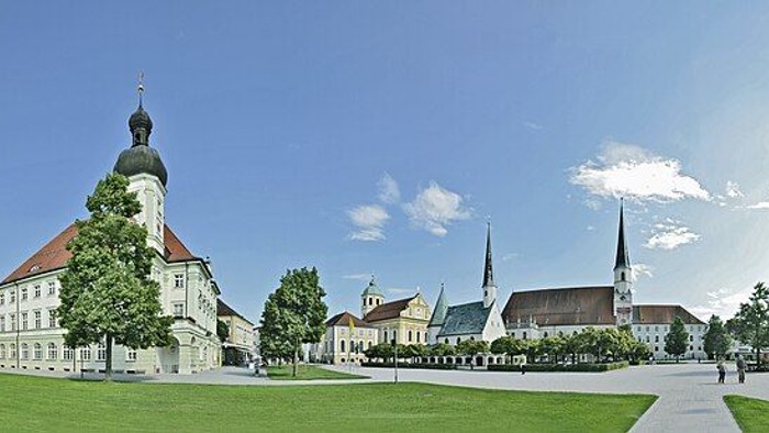 Der Kapellplatz in Altötting als Panoramabild mit einem Platz und Rasen im Vordergrund und Kirchen und Gebäuden im Hintergrund