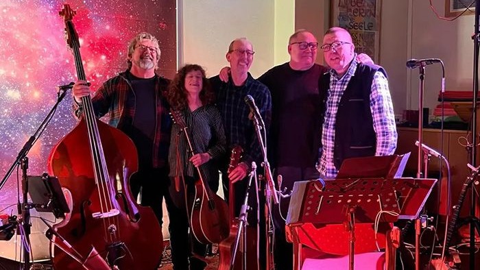 Das Bild zeigt die Band Liederstand. Es sind 4 Männer und eine Frau abgebildet. Die Personen sind zwischen 50 und 65 Jahren alt. Sie halten teilweise Instrumente in den Händen.