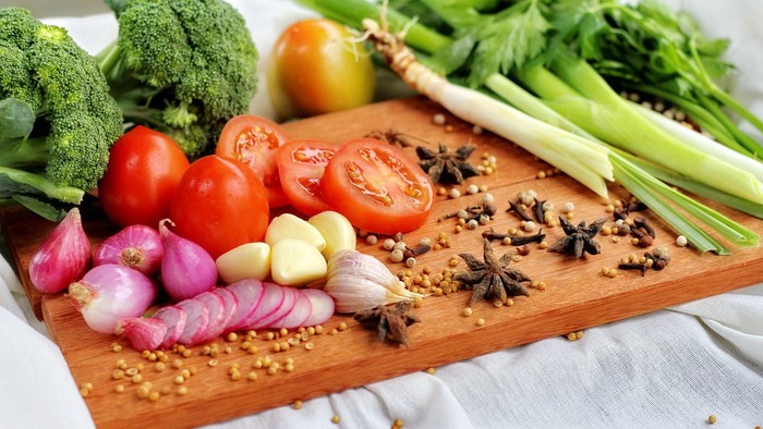 Das Bild zeigt verschiedene Gemüsesorten und Gewürze auf einem Schneidebrett