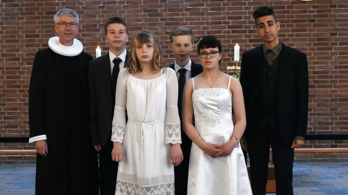 En præst og fem børn i kirkesal.