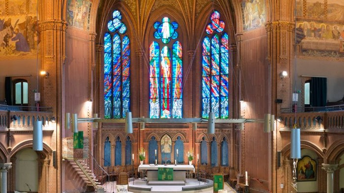 Die Kirche hat bunte Glasfenster und eine große Decke.