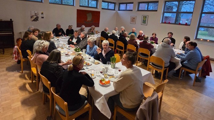 Viele Menschen sitzen im Saal des Elsa-Brändström-Haus am gedeckten Tisch.