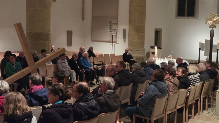 Man sieht die Gemeinde in der Christuskirche, im Mittelgang liegt ein großes Holzkreuz.