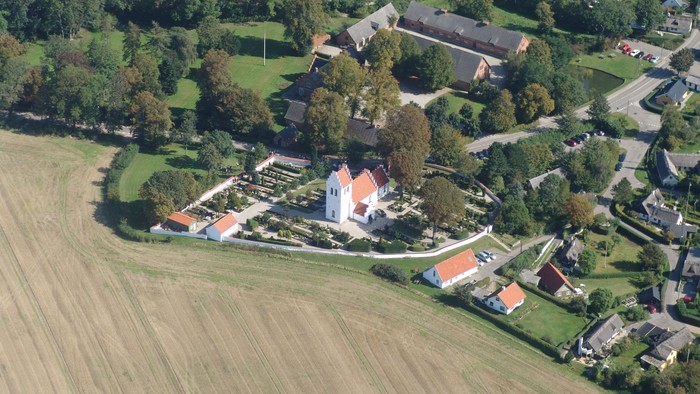 En lille landsby med kirke og huse omgivet af marker og skove