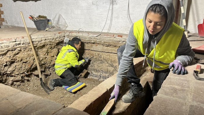 Thai Nguy (l.) und Joana Laura Noack vom archäologischen Team der Stadt Lübeck legen die Wandmalereien in einer historischen Gruft frei. 
