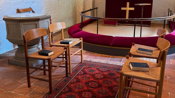 To stolepar er opstillet overfor hinanden foran alteret, som ved en vielsesceremoni.