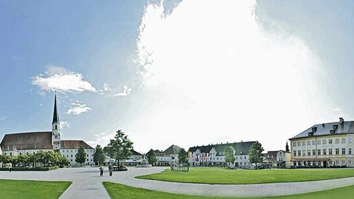 Der Kapellplatz in Altötting als Panoramabild mit einem Platz und Rasen im Vordergrund und Kirchen und Gebäuden im Hintergrund