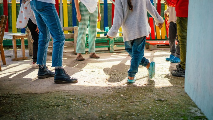 Kinder, die auf einem Spielplatz mit buntem Spielgerät spielen und laufen, tragen Outdoor-Schuhe.