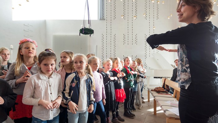 En lærer leder en gruppe unge elever i en interaktiv indendørs lektion eller aktivitet.