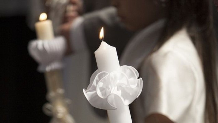 Person hält brennende Kerze in weißem Gewand