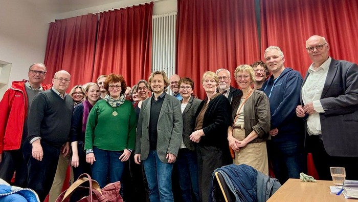 Gruppe von Menschen, die drinnen für ein Foto posieren, während einer scheinbar formellen oder feierlichen Veranstaltung.