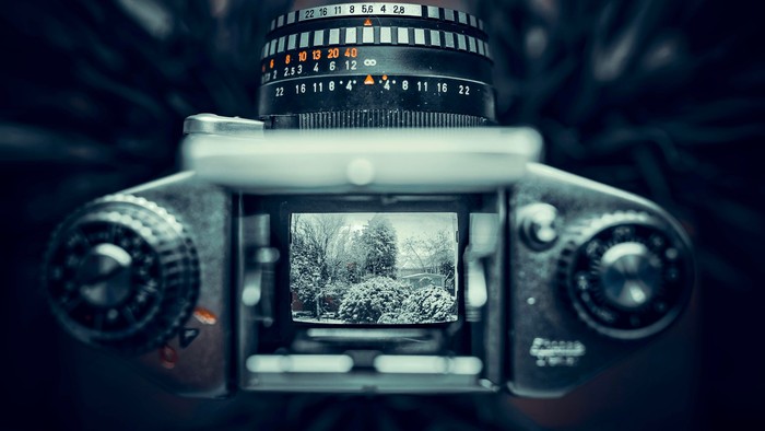 Gammelt kamera med et delvist eksponeret sort-hvidt filmbillede af et sløret landskabsscene.