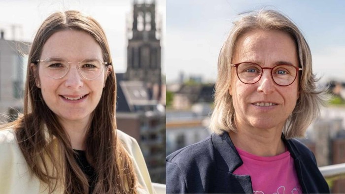 Zwei Frauen, die draußen lächeln: eine jüngere mit Brille und leichter Jacke, die andere ältere in einem Blazer und rosafarbenem Hemd.