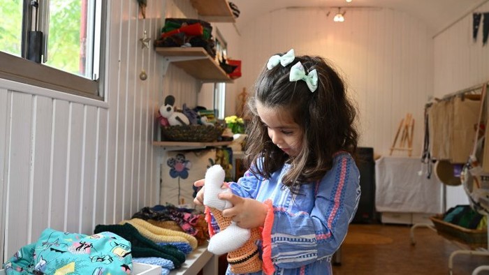 Junges Mädchen, das vorsichtig ein Stofftier in einem bunten, ordentlichen Indoor-Spielbereich hält.