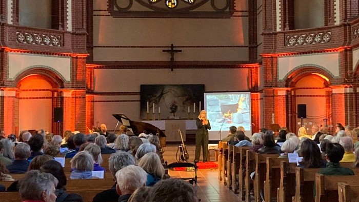 Blick in die voll besetzte Kirche während einer musikalischen Darbietung vor dem Altarbereich.