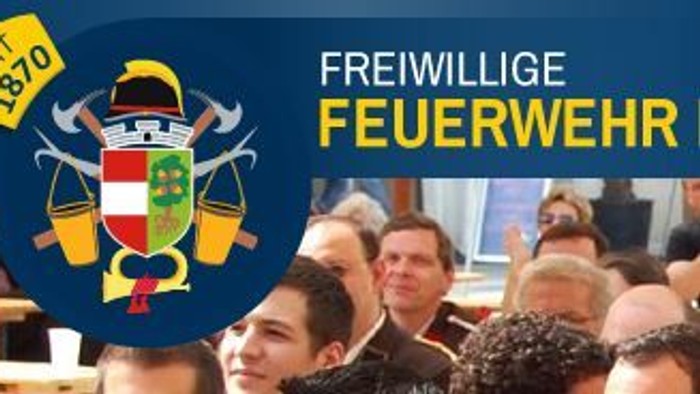 Eine Gruppe feiert das 1470-jährige Jubiläum einer Freiwilligen Feuerwehr mit festlicher Kleidung und Abzeichen.