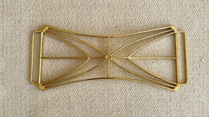 En guldtonet metalhårbøjle med et indviklet krydsmønster.