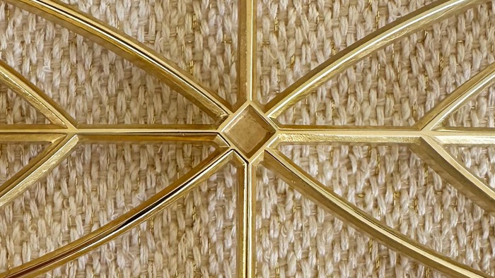 Indviklet gyldent geometrisk mønster på vævet stråloft.