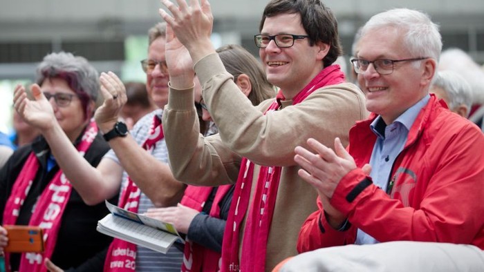 Begeisterte Fans jubeln und klatschen enthusiastisch bei einer Sportveranstaltung und tragen passende rot-rosa Schals.