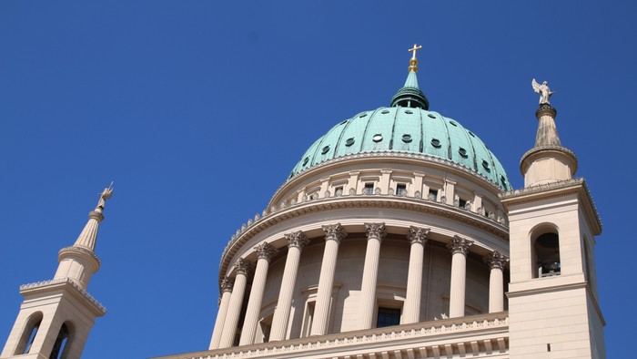 Großartige Kuppelkirche mit grünem Dom und zwei Türmen vor blauem Himmel