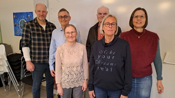 En gruppe af seks personer står sammen i et rum.