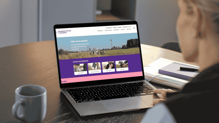 Eine Person, die mit einem Laptop eine Website mit einem sauberen, professionellen Design und Outdoor-Bildern durchstöbert.