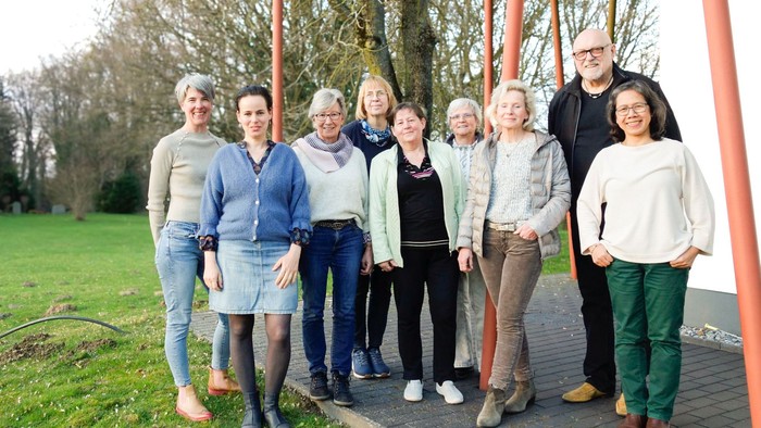 Eine gemischte Gruppe lächelnder Menschen vor einem parkartigen Gelände