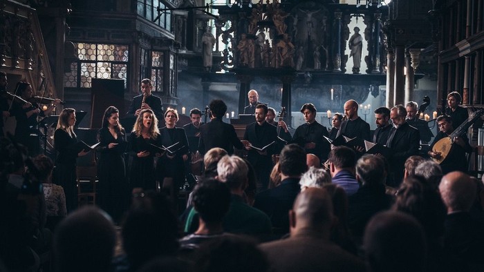 Ein Chor aus Frauen und Männern singt in einer alten Kirche.