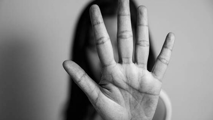 Eine Hand, die in einer blockierenden oder stoppenden Geste erhoben ist, vor einem unscharfen Hintergrund.