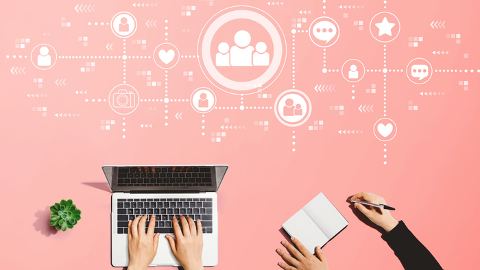 Eine Person arbeitet an einem Laptop, während eine andere ein Buch hält, umgeben von Social Media Symbolen
